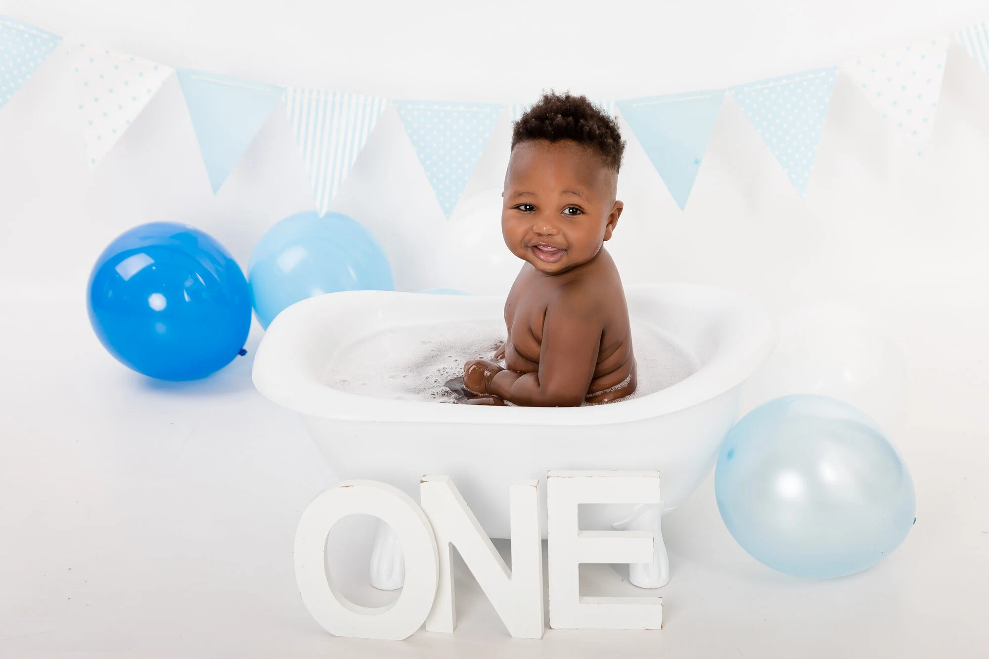 Blue bunting and balloon splash setup with a white bath tub