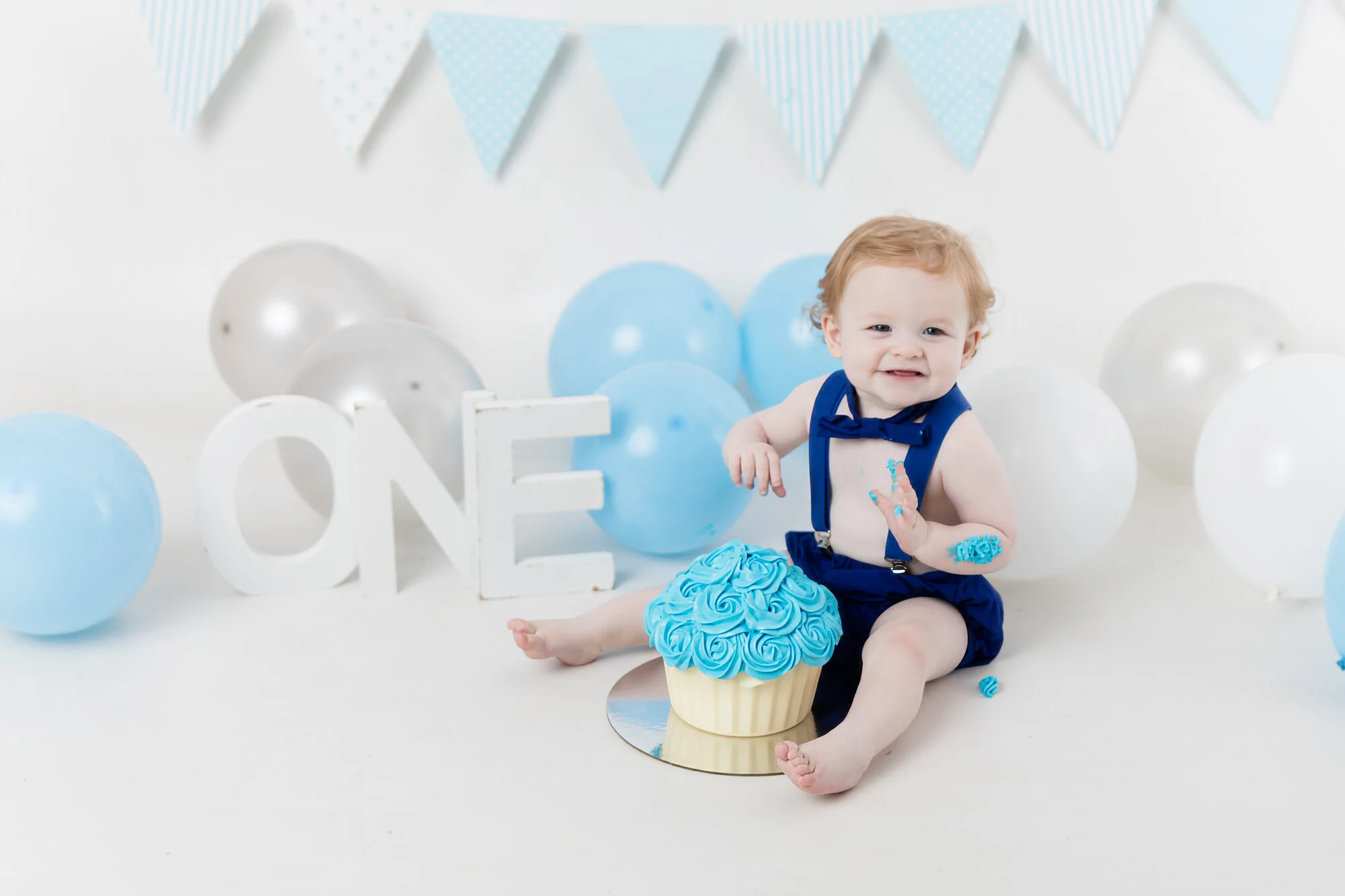 Blue and white balloon cake smash setup with large ONE letters