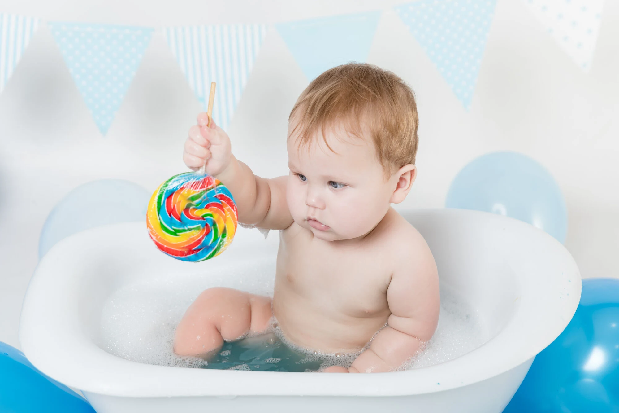 Cake smash splash setup with a bath tub and a colourful lollipop prop