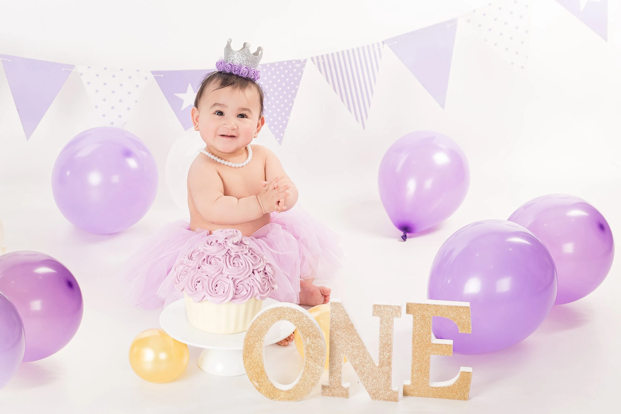 Purple and lilac balloon cake smash setup with crown and ONE letters